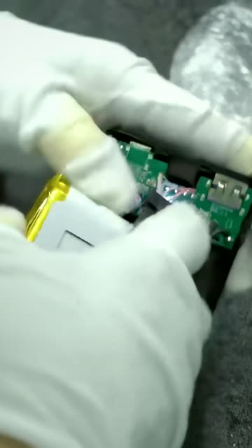 Gloved hands assembling a circuit board